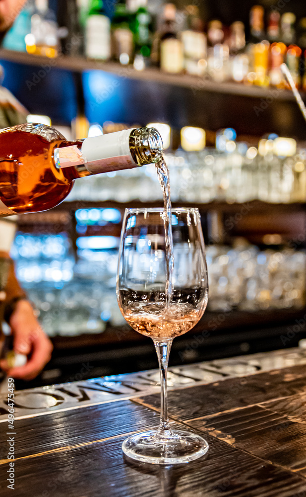 bartender pouring rose wine into a glass in cafe or bar