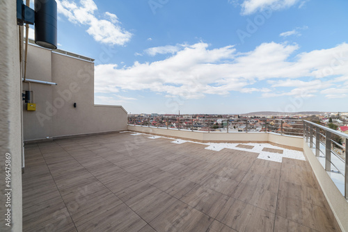 large clean balcony with dark tiles under the blue sky
