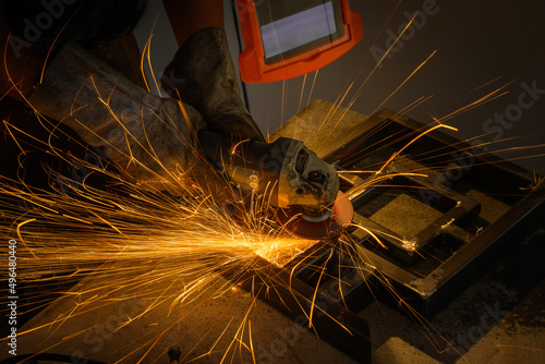 Male worker working at home with a grinder. golden sparks of Steel workpieces wear protective masks and wear protective gloves to prevent sparks from steel grinders.