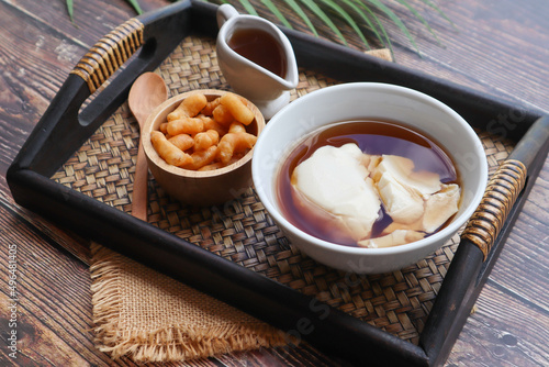 DouHua - soft tofu pudding ( soy bean curd) , famous asian healthy dessert served in tray on wood table at close up view 