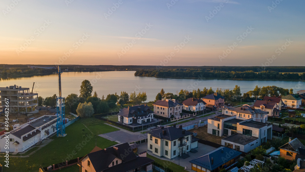 Aerial sunset panorama view of luxury upscale residential neighborhood gated community street near lake.