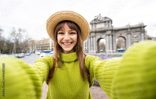 Beautiful female tourist taking selfie at Puerta de Alcala in Madrid, Spain - Happy young woman having fun on european city street - Girl smiling at camera outside