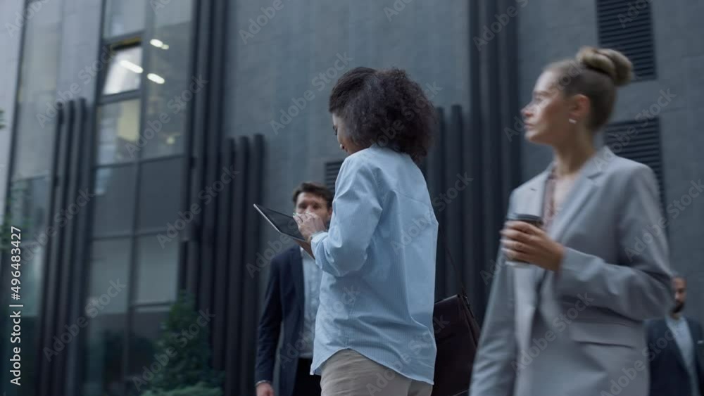 Smiling woman using tablet computer in downtown district. Corporate people going Smiling woman using tablet computer in downtown district. Corporate people going