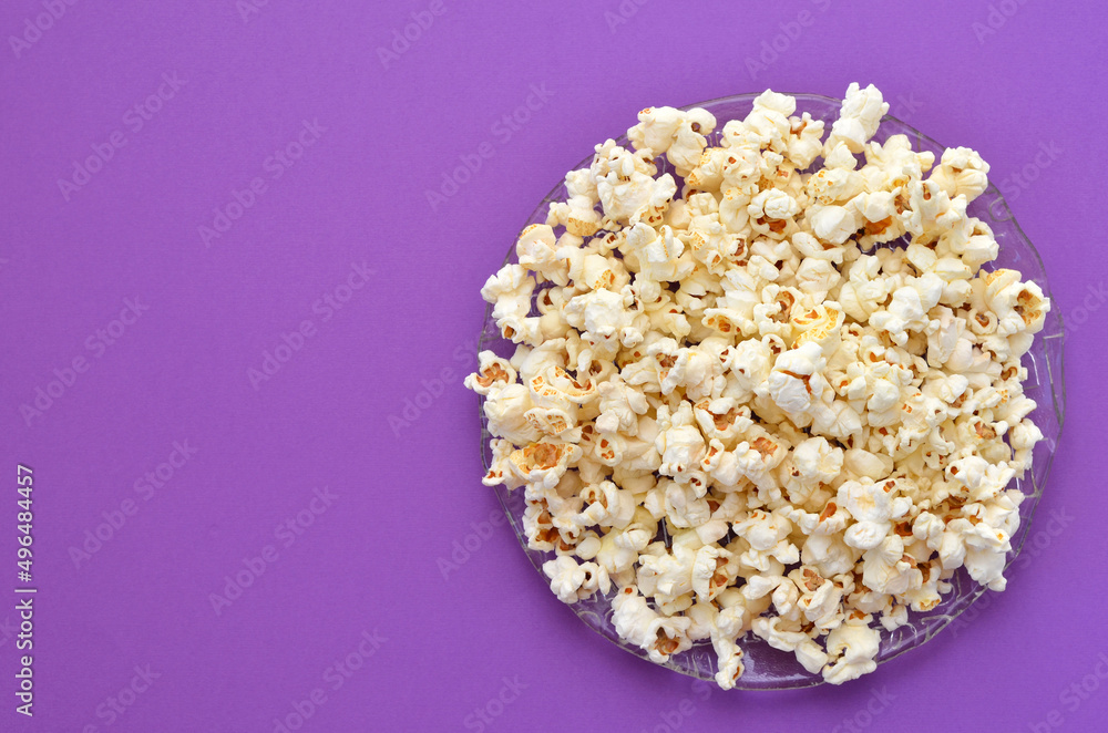 a plate of popcorn on a purple background, copy space a plate of popcorn on a purple background, copy space