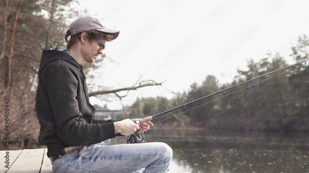 A young guy catches a predatory fish on spinning from the shore. Fishing as a hobby. A young guy catches a predatory fish on spinning from the shore. Fishing as a hobby.