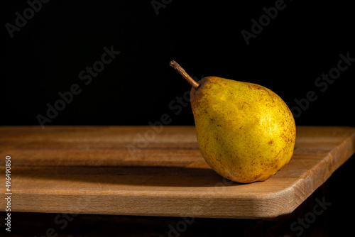 Gruszka na desce z czarnym tłem. Pear on board with black background.