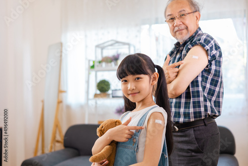 Senior man after vaccination and granddaughter at home. Virus protection. COVID-2019.Vaccination in the shoulder of child patient at home.