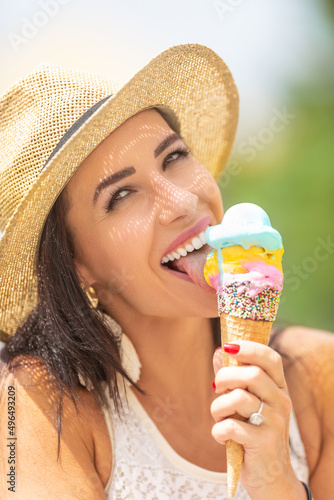 Beautiful happy woman licks ice cream during a hot summer day