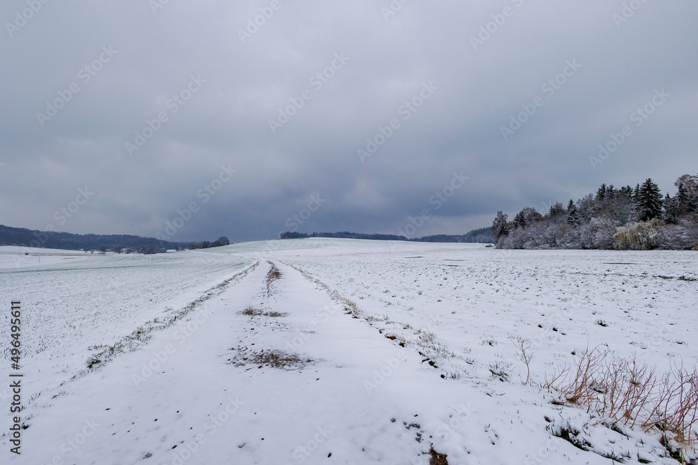 snowy field path with cloudy sky in Schmuttertal biotope near the village of Gablingen near Augsburg in Bavaria, Germany snowy field path with cloudy sky in Schmuttertal biotope near the village of Gablingen near Augsburg in Bavaria, Germany
