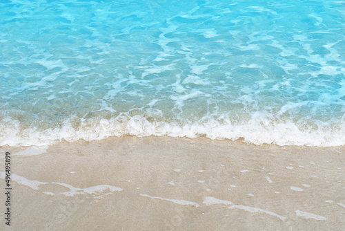 Soft blue ocean wave on sandy beach for texture copy space and background