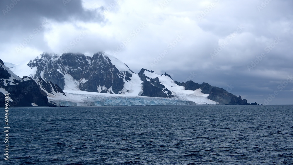 Glacier meeting the Southern Ocean at the base of a rugged mountain in Antarctica