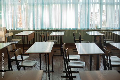 Desks for students at school. Classroom is empty. Chairs and tables are in row.