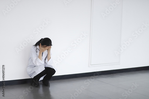 Tired doctor sitting on floor in hospital