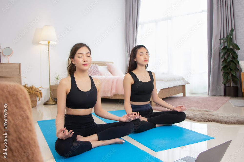 Two beautiful Asian girls wearing workout clothes and smiling with dogs in bedroom. woman on exercise mat with dumbbells and tablet Two beautiful Asian girls wearing workout clothes and smiling with dogs in bedroom. woman on exercise mat with dumbbells and tablet