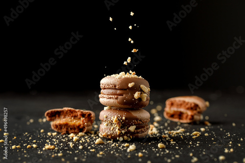 Chocolate macarons with biscuit flakes and black background.
