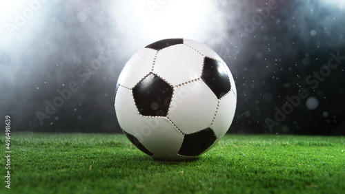Soccer ball on grass with dark background and lights