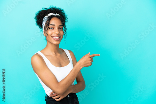 Young latin woman isolated on blue background pointing finger to the side