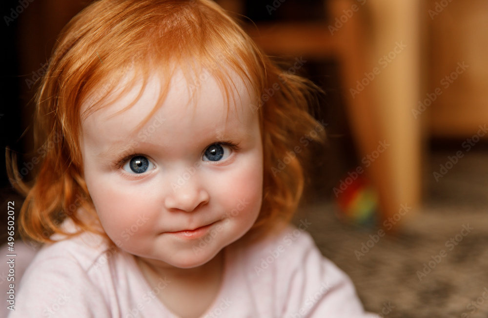 Red hair baby on the floor. Child laying on the carpet at home and looking at the camera. Portrait of the cute infant girl Red hair baby on the floor. Child laying on the carpet at home and looking at the camera. Portrait of the cute infant girl