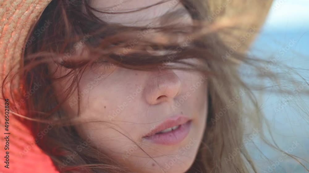 Attractive Caucasian young woman in a straw hat in the wind near the seashore. Slow motion. Shallow depth of field Attractive Caucasian young woman in a straw hat in the wind near the seashore. Slow motion. Shallow depth of field