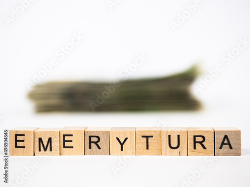 Word retirement written in polish with wooden blocks with money in the background, "emerytura" means retirement