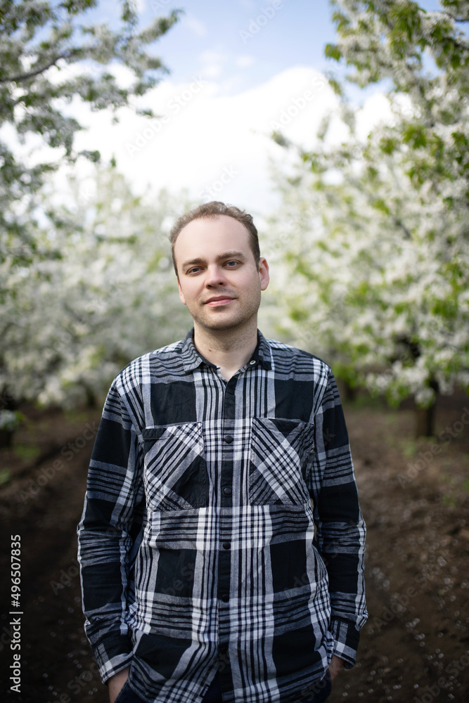 Portrait of a farmer on agricultural land. Blooming gardens in spring.