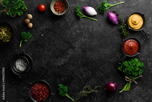 Black stone cooking background. Spices and vegetables. Top view. Free space for your text.
