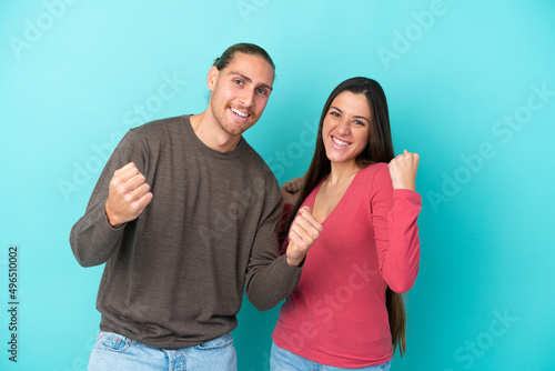Young caucasian couple isolated on blue background celebrating a victory in winner position