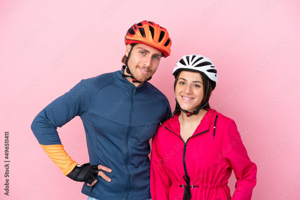 Young cyclist caucasian people isolated on pink background posing with arms at hip and smiling Young cyclist caucasian people isolated on pink background posing with arms at hip and smiling