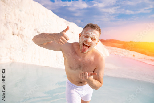 Happy tourist man on background denizli travertine pools blue water in Pamukkale Turkey sunlight. Concept natural beauty spa procedures for skin
