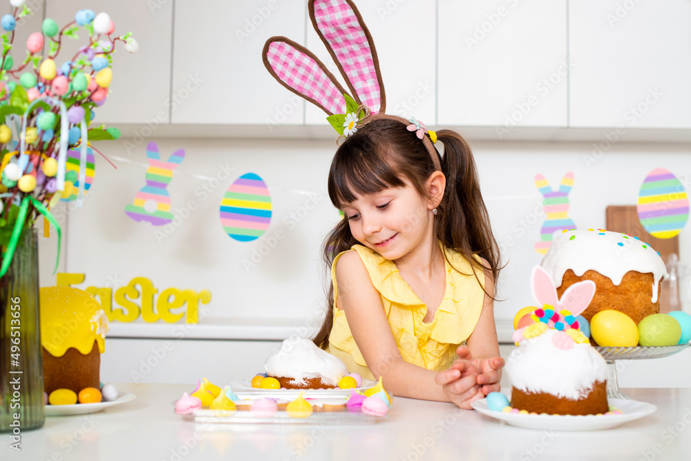 Little girl 6 years old with rabbit ears decorates Easter cake in the kitchen Little girl 6 years old with rabbit ears decorates Easter cake in the kitchen