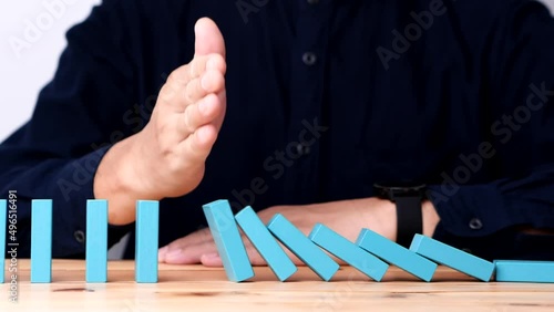 Businessman hand stopping continuous failing domino wooden effect. Concept of Risk Management, Business Crisis, Domino Effect, Investment, Finance, Risk, Disaster, Protection, Prevention, Opportunity