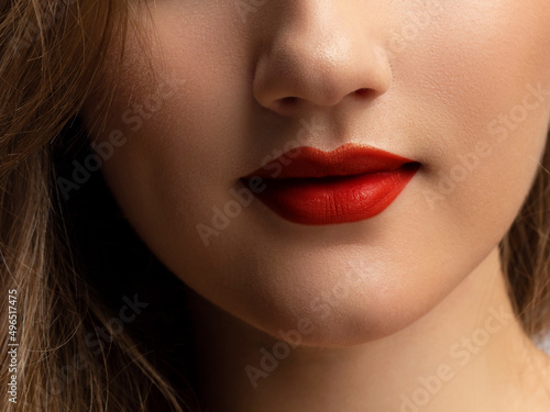 Cosmetics  makeup and trends. Bright lip gloss and lipstick on lips. Closeup of beautiful female mouth with red and pink lip makeup. Beautiful part of female face. Perfect clean skin