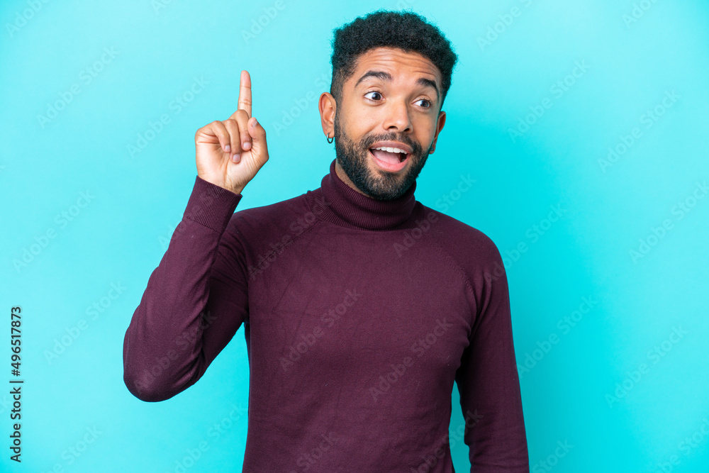 Young Brazilian man isolated on blue background intending to realizes the solution while lifting a finger up Young Brazilian man isolated on blue background intending to realizes the solution while lifting a finger up