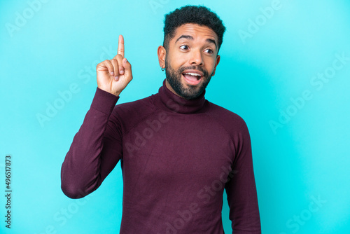Young Brazilian man isolated on blue background intending to realizes the solution while lifting a finger up