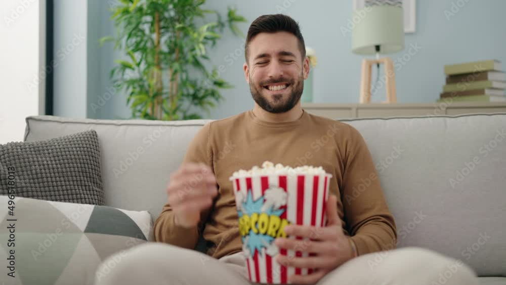 Young hispanic man watching movie sitting on sofa at home Young hispanic man watching movie sitting on sofa at home