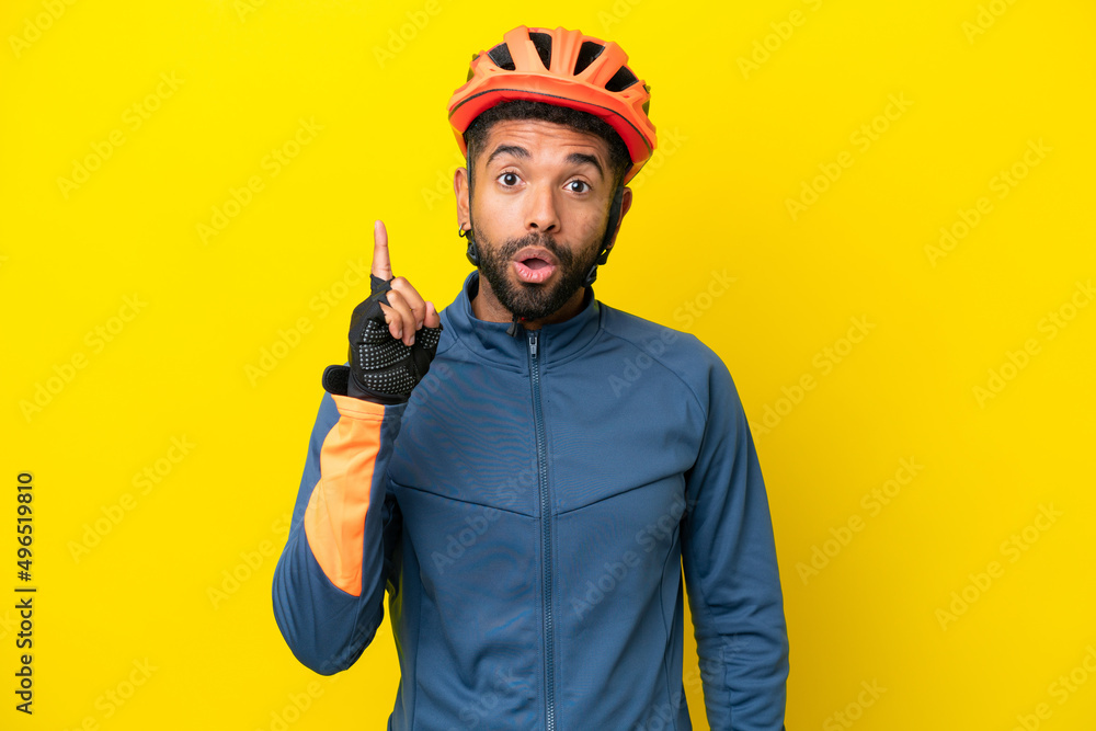 Young cyclist Brazilian man isolated on yellow background intending to realizes the solution while lifting a finger up