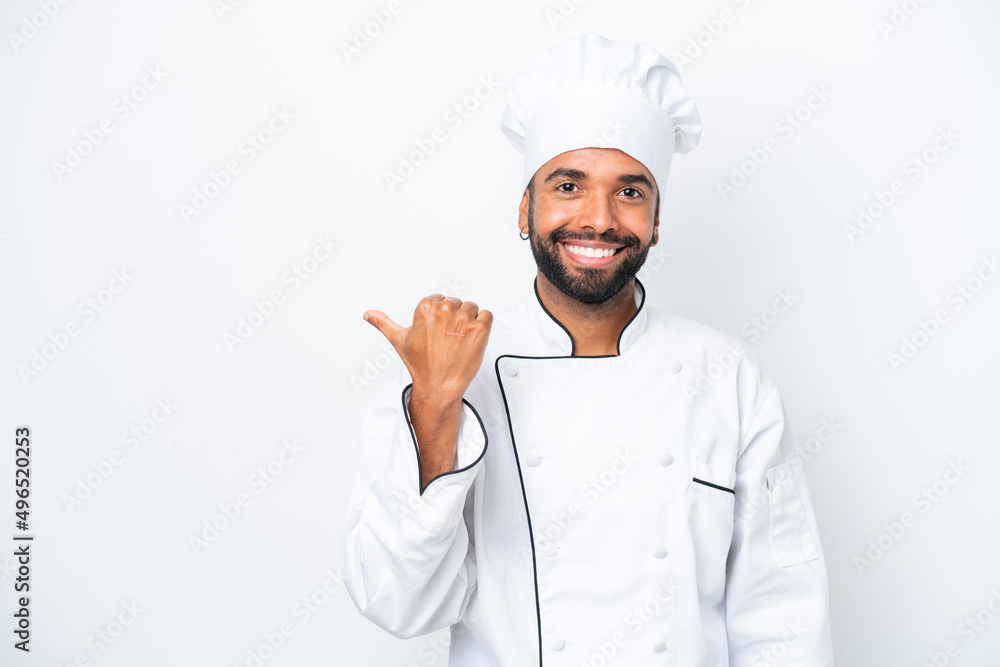 Young Brazilian chef man isolated on white background pointing to the side to present a product Young Brazilian chef man isolated on white background pointing to the side to present a product