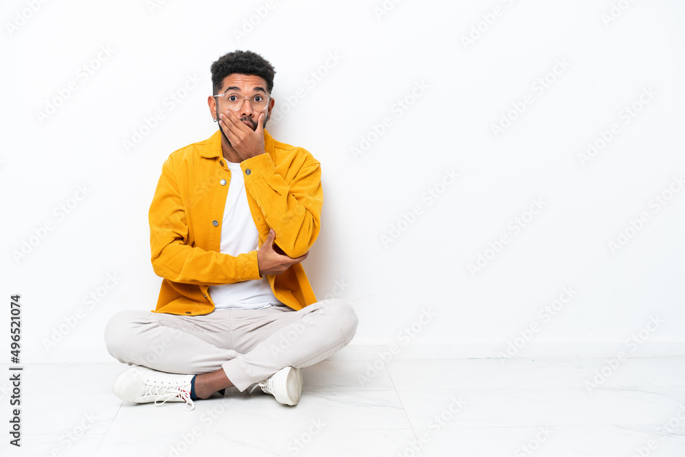 Young Brazilian man sitting on the floor isolated on white background surprised and shocked while looking right Young Brazilian man sitting on the floor isolated on white background surprised and shocked while looking right