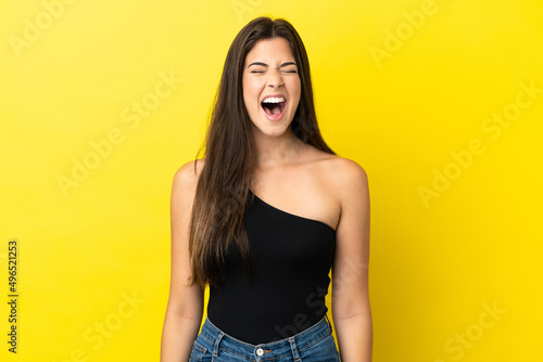Young Brazilian woman isolated on yellow background shouting to the front with mouth wide open © luismolinero