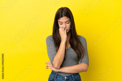 Young Brazilian woman isolated on yellow background having doubts