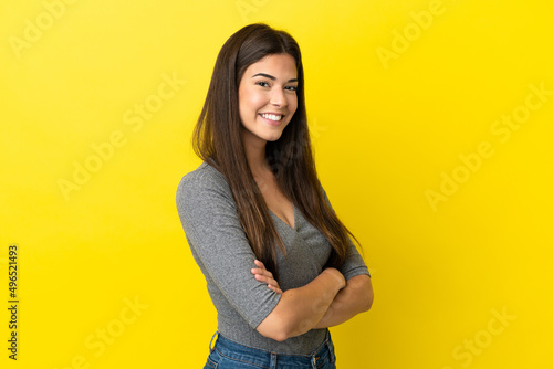 Young Brazilian woman isolated on yellow background with arms crossed and looking forward