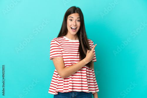 Young Brazilian woman isolated on blue background surprised and pointing side © luismolinero