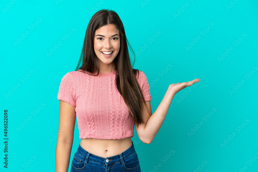 Young Brazilian woman isolated on blue background holding copyspace imaginary on the palm to insert an ad Young Brazilian woman isolated on blue background holding copyspace imaginary on the palm to insert an ad