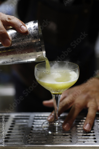 barman vertiendo el licor de una coctelera en copa de coctel