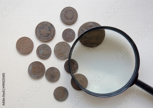 Pile of vintage metall (copper) coins. Magnifying glass and coins of the Russian Empire in the background kopyur. Antikvariat. Numismatics vintage background