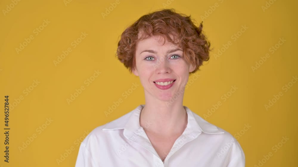 Pretty smiling redhead woman in white shirt smiling and looking at the camera isolated on yellow background. People sincere emotions lifestyle concept. emotions. Pretty smiling redhead woman in white shirt smiling and looking at the camera isolated on yellow background. People sincere emotions lifestyle concept. emotions.
