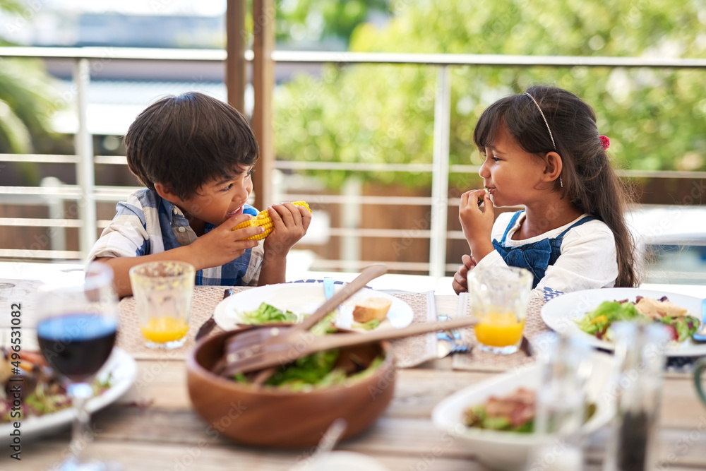 Growing bodies need lots of healthy meals. Shot of two adorable little children enjoying a meal together outdoors.
