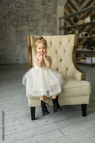 Obraz na płótnie .a little girl sits on a beautiful armchair in a photo studio w salonie