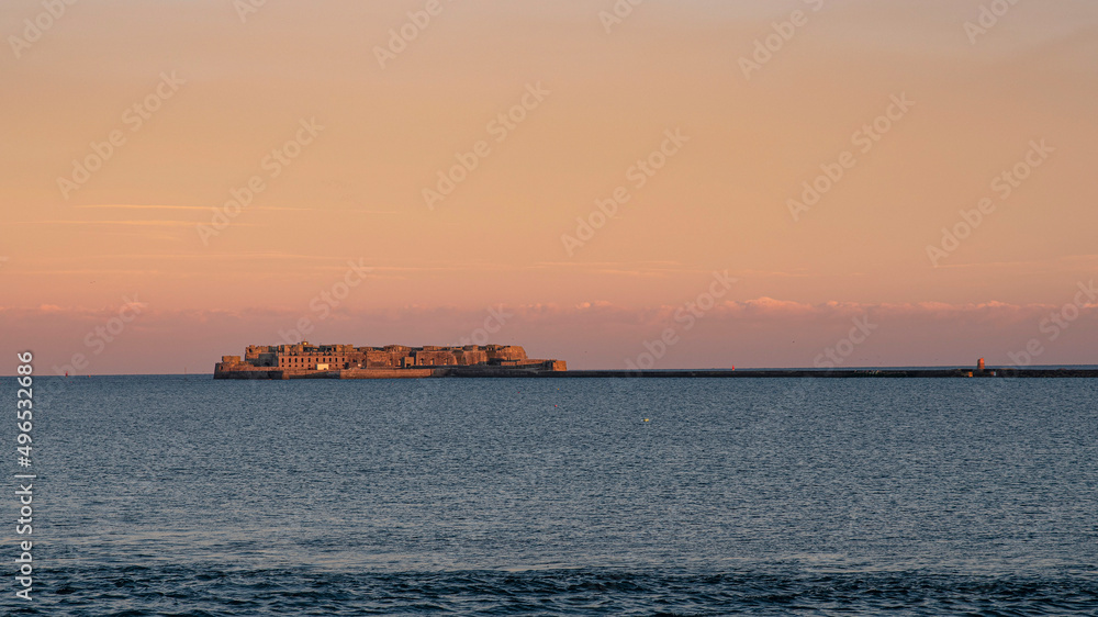 Old fortification under a sunset in the sea off Cherbourg