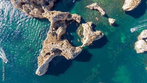 Aerial drone shot of kayaks and boats passing around magical Ponta da Piedade limestone cliffs. Exploring caves and tunnels of Lagos, Algarve, South of Portugal. Travel and adventure. Nomad life.
